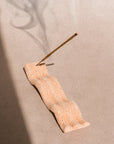 Elongated tray incense holder with imprinted wave pattern. The Wave of Senses symbolizes the undulating motion made by incense fragrance as it disperses throughout the room. The Wave holds the incense stick and catches ash as it falls.