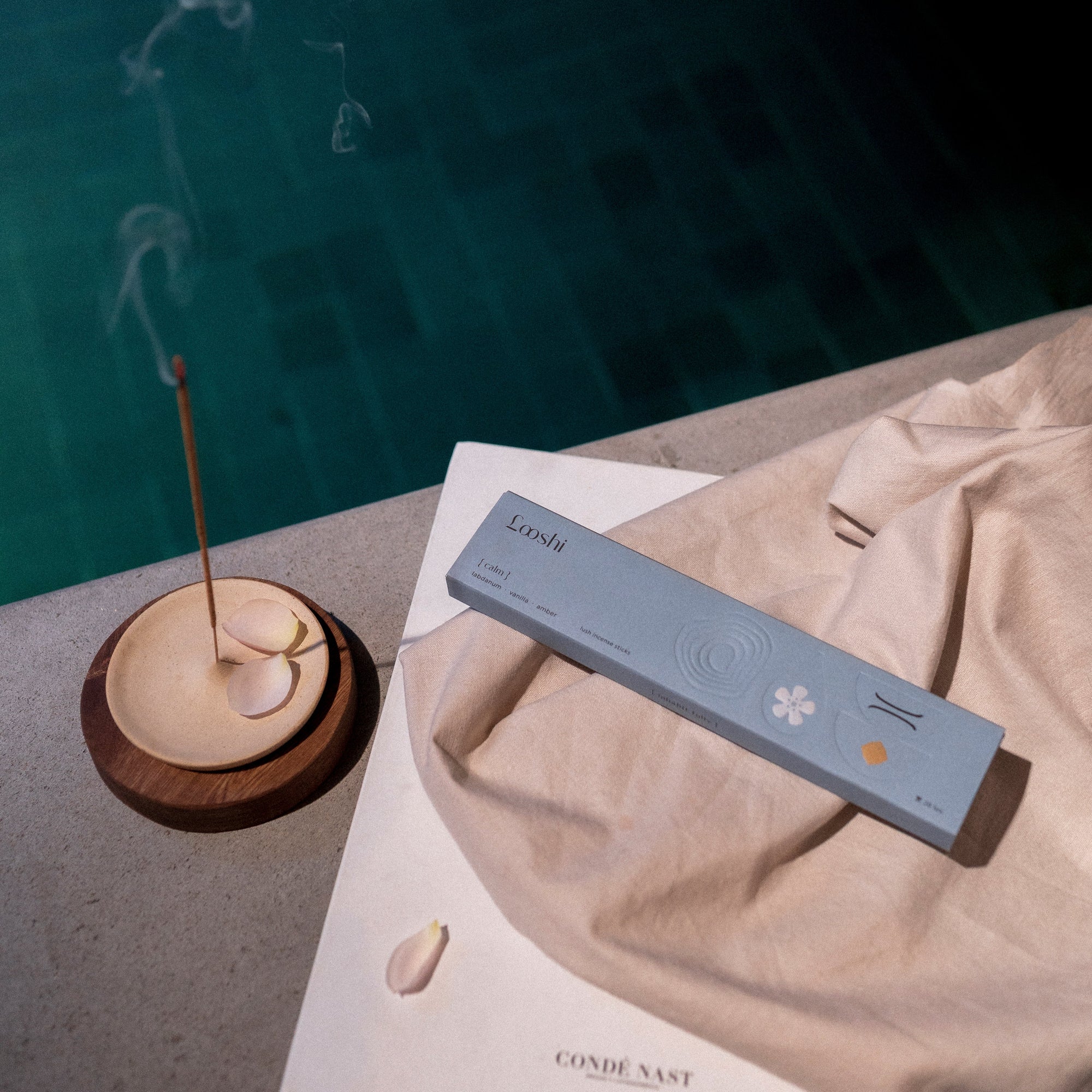 Incense stick with smoke and a box labeled 'Calm' on a textured surface.
