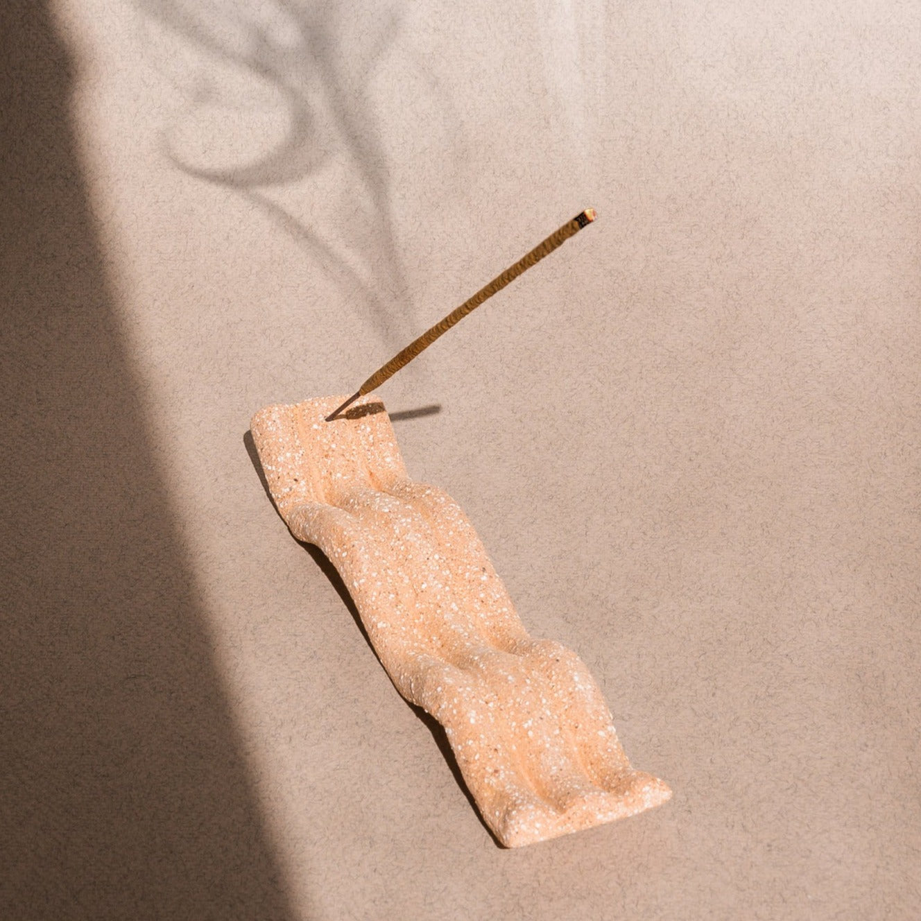 Elongated tray incense holder with imprinted wave pattern. The Wave of Senses symbolizes the undulating motion made by incense fragrance as it disperses throughout the room. The Wave holds the incense stick and catches ash as it falls.
